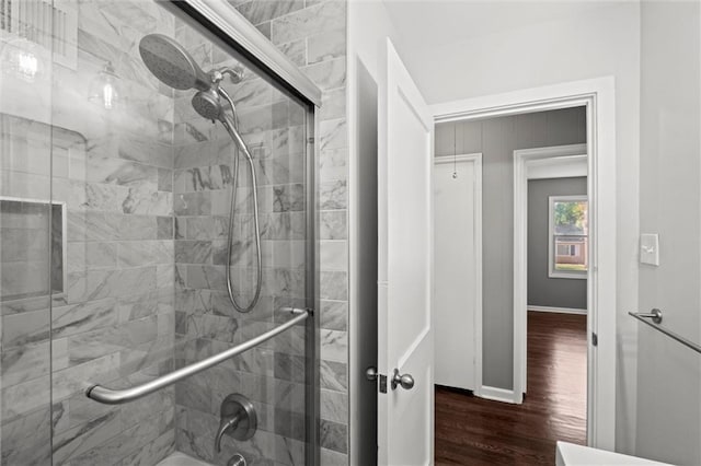bathroom with wood finished floors, enclosed tub / shower combo, and baseboards