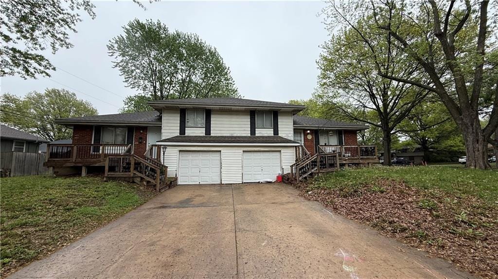 tri-level home featuring a garage, brick siding, concrete driveway, a porch, and stairway