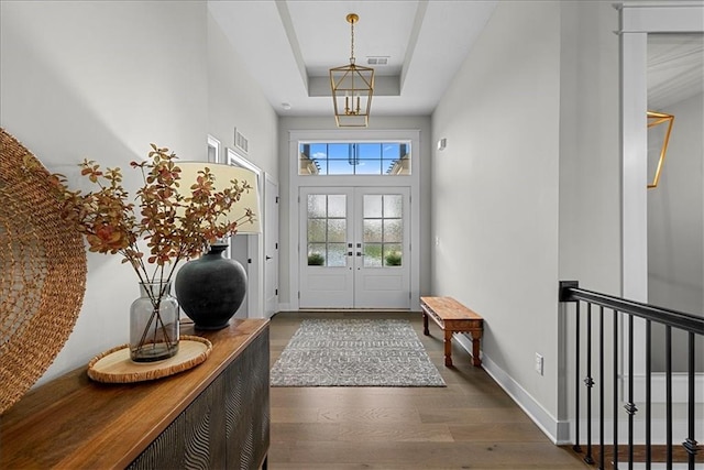 entryway with a raised ceiling, baseboards, wood finished floors, and visible vents