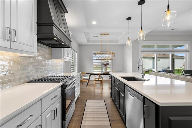 kitchen featuring crown molding, appliances with stainless steel finishes, a sink, decorative backsplash, and custom exhaust hood
