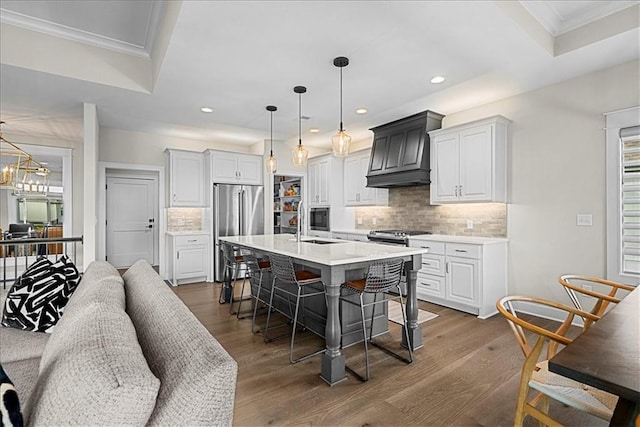 kitchen featuring a breakfast bar area, premium range hood, light countertops, tasteful backsplash, and appliances with stainless steel finishes