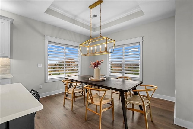 dining area with dark wood-style flooring, baseboards, a chandelier, ornamental molding, and a tray ceiling