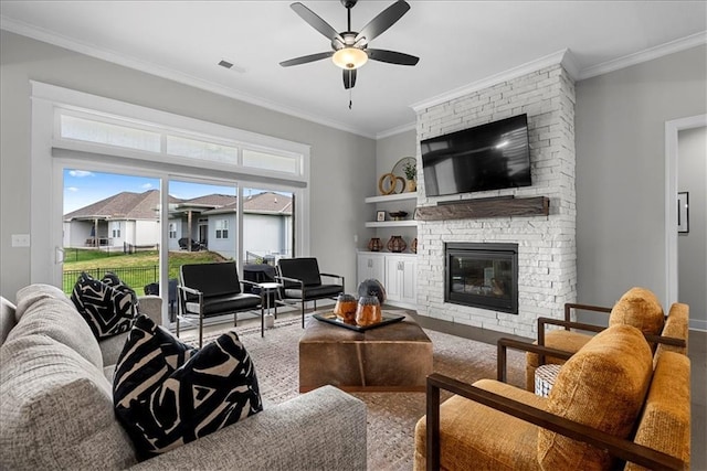 living room with visible vents, crown molding, a stone fireplace, and ceiling fan