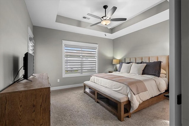 bedroom with a ceiling fan, visible vents, baseboards, a tray ceiling, and carpet flooring