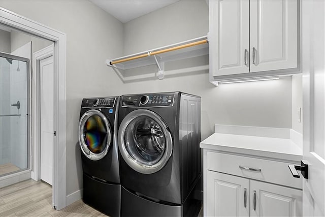 clothes washing area featuring cabinet space, baseboards, washer and clothes dryer, and light wood finished floors