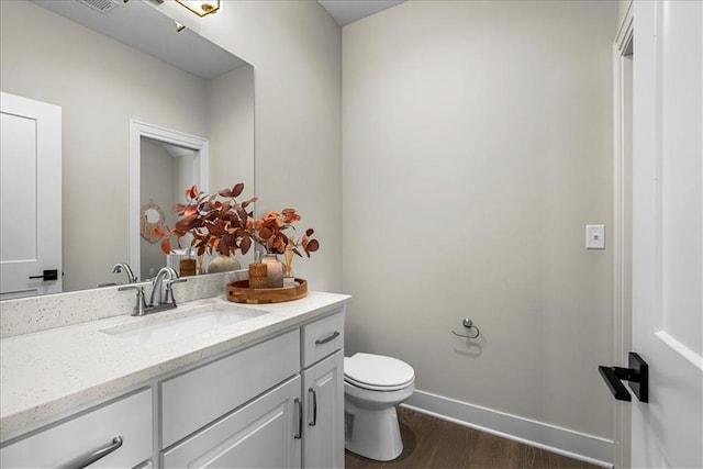 bathroom with toilet, baseboards, wood finished floors, and vanity