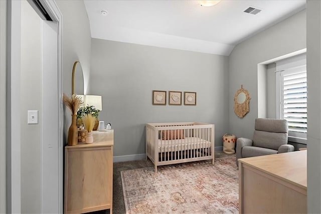 carpeted bedroom with baseboards, vaulted ceiling, a crib, and visible vents
