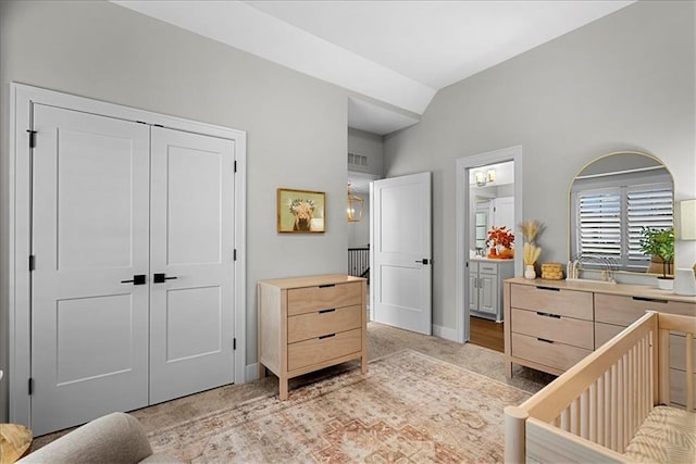 bedroom featuring a closet, visible vents, lofted ceiling, light carpet, and baseboards