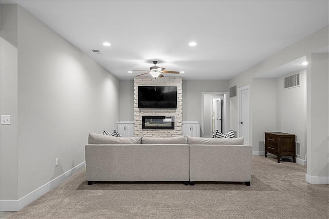 carpeted living area featuring baseboards, a ceiling fan, a stone fireplace, and visible vents