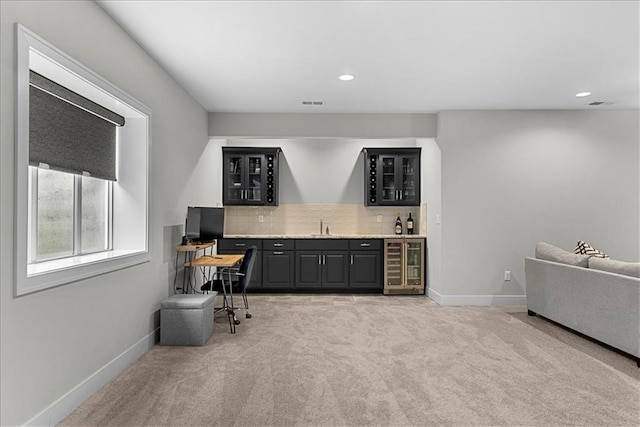 bar with light carpet, beverage cooler, indoor wet bar, baseboards, and decorative backsplash