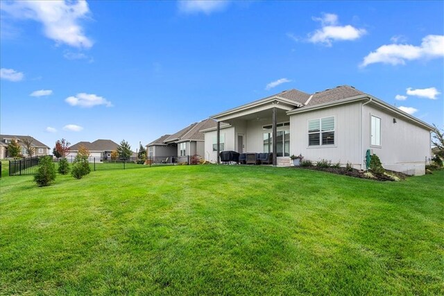 rear view of house with a lawn, a ceiling fan, and fence