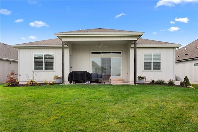 rear view of property featuring a shingled roof, ceiling fan, a yard, and a patio area