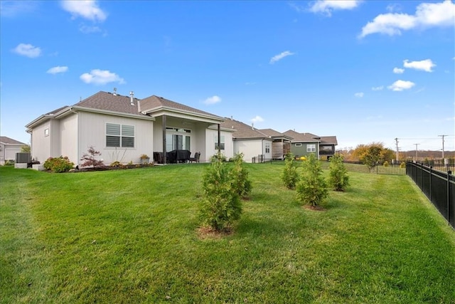 back of house with a lawn and fence