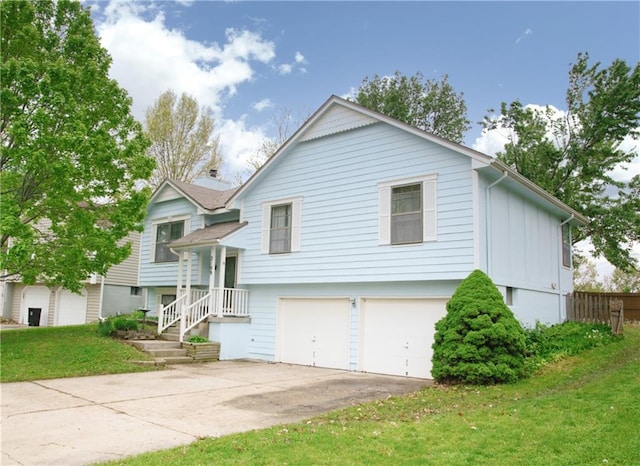 raised ranch with a garage, fence, driveway, and a front yard