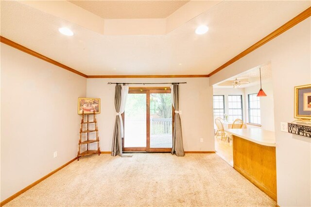 carpeted spare room with crown molding, baseboards, and a healthy amount of sunlight