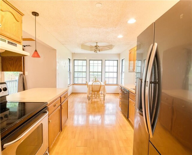 kitchen with ceiling fan, a textured ceiling, light wood finished floors, under cabinet range hood, and stainless steel appliances