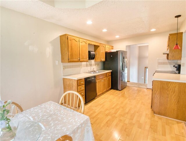 kitchen with backsplash, stove, light countertops, black dishwasher, and light wood-style flooring