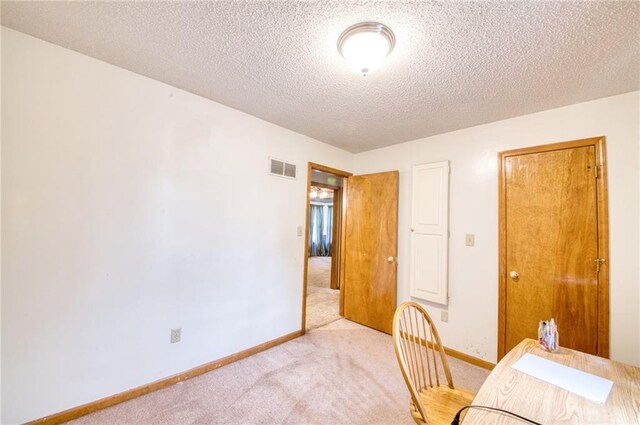 home office featuring a textured ceiling, baseboards, light colored carpet, and visible vents
