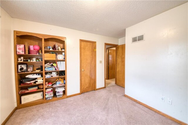 unfurnished bedroom with visible vents, a textured ceiling, carpet, and baseboards