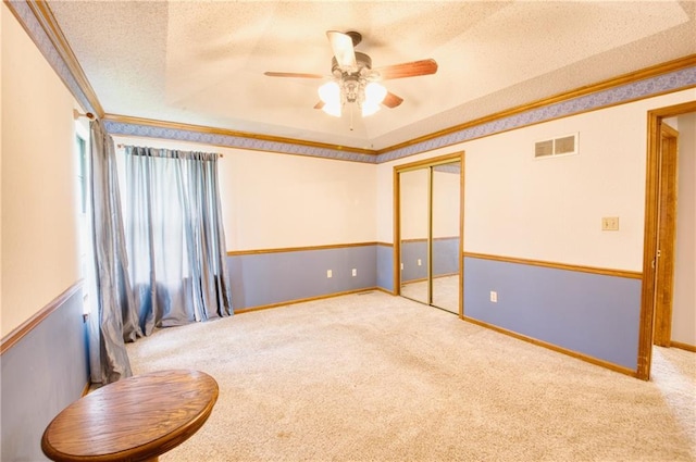 unfurnished room featuring visible vents, carpet, a textured ceiling, and ceiling fan