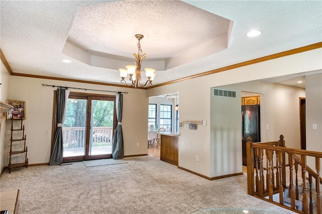 2109 NW Hidden Pointe Ct, Blue Springs, MO 64015 - spare room featuring a textured ceiling, light colored carpet, a chandelier, a tray ceiling, and ornamental molding