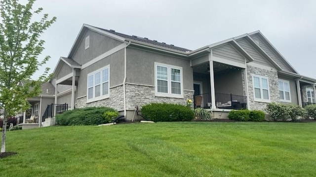 rear view of property with a lawn, stucco siding, and stone siding