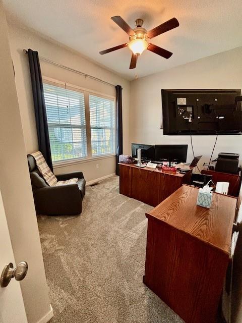 office space featuring baseboards, ceiling fan, and carpet