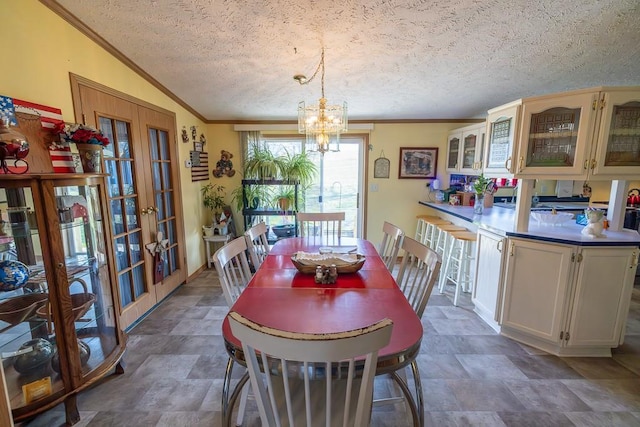 dining area with a chandelier, stone finish flooring, crown molding, a textured ceiling, and french doors