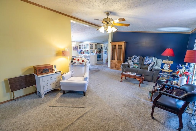living room featuring ceiling fan, carpet, baseboards, ornamental molding, and a textured ceiling