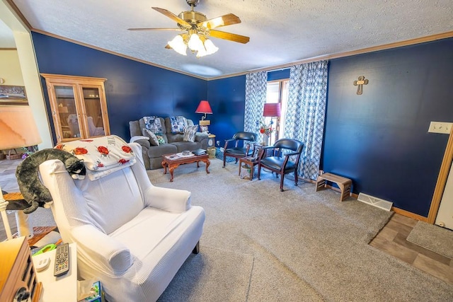 living area with crown molding, a textured ceiling, visible vents, and a ceiling fan