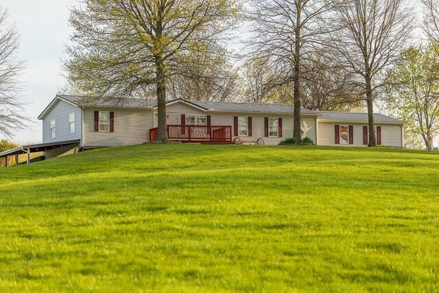 rear view of property with a deck, metal roof, and a yard