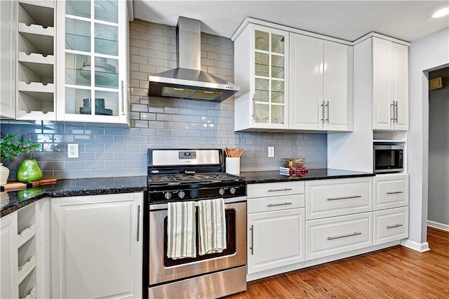kitchen featuring decorative backsplash, stainless steel appliances, white cabinetry, and wall chimney exhaust hood