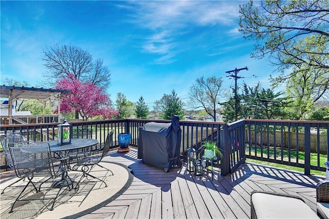 wooden deck featuring outdoor dining area, a fenced backyard, and a grill