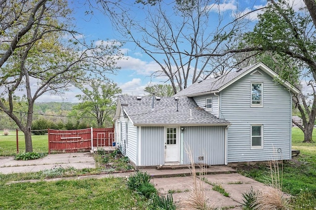 rear view of property with board and batten siding, fence, and a shingled roof