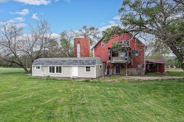 rear view of house with an outdoor structure, a chimney, and a yard