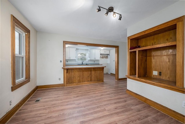unfurnished living room with visible vents, baseboards, and wood finished floors
