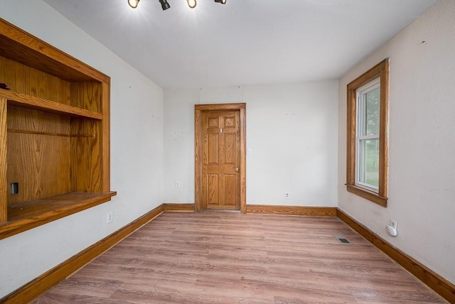 unfurnished room with light wood-style floors, baseboards, and visible vents