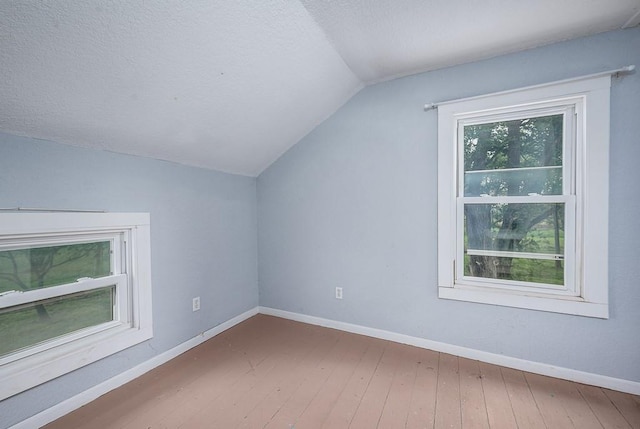 additional living space with baseboards, vaulted ceiling, and hardwood / wood-style flooring
