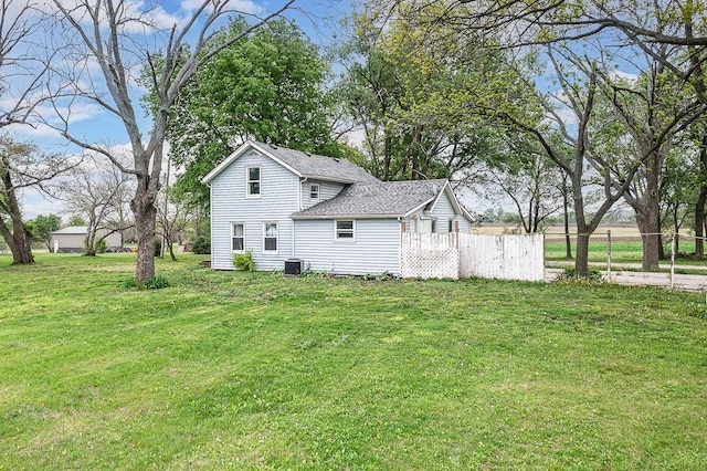view of side of property featuring fence, a shingled roof, a yard, and cooling unit