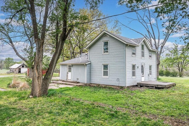 rear view of property with a lawn, a wooden deck, and a shingled roof