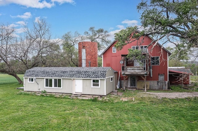 rear view of property with a lawn and an outbuilding