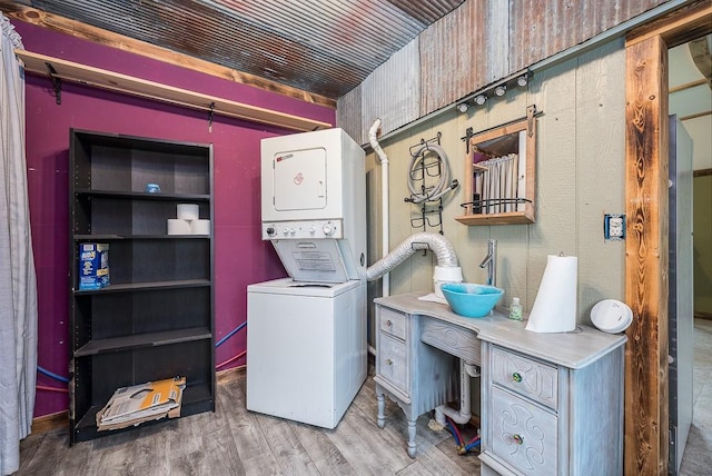 laundry room with stacked washer and clothes dryer and wood finished floors