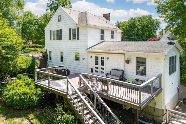 back of property featuring a shingled roof, a chimney, stairs, and a wooden deck
