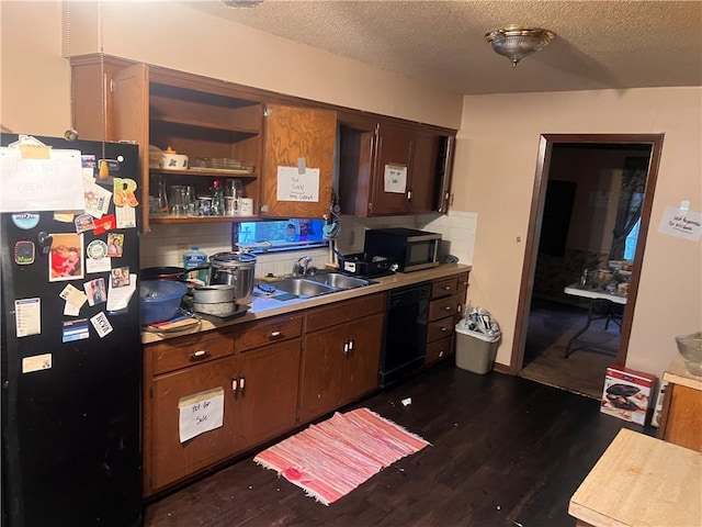 kitchen featuring a sink, black appliances, dark wood-style flooring, and a textured ceiling