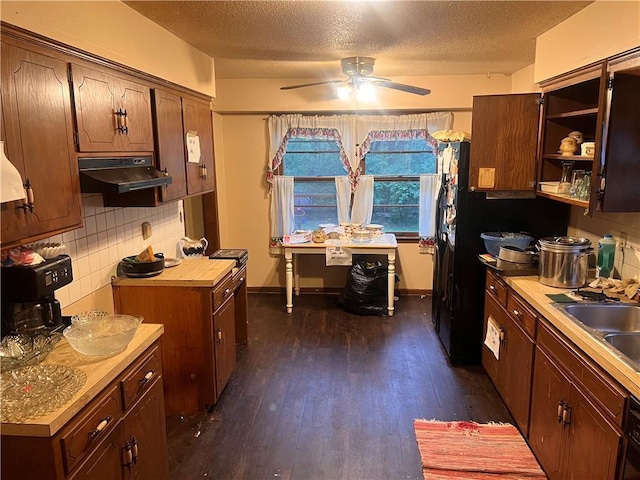 kitchen with a textured ceiling, a ceiling fan, tasteful backsplash, under cabinet range hood, and dark wood-type flooring