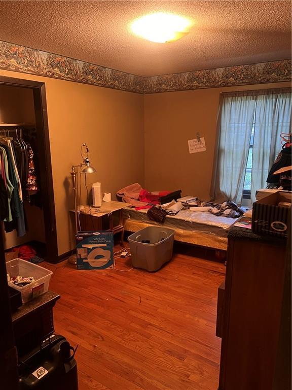 bedroom with a textured ceiling, a closet, and wood finished floors