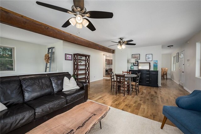 living area with a ceiling fan, baseboards, and wood finished floors