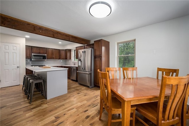 dining room with recessed lighting, beam ceiling, and light wood-style flooring