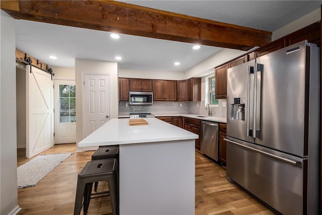 kitchen with plenty of natural light, a barn door, beamed ceiling, and stainless steel appliances