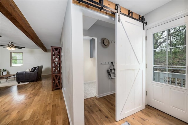 interior space featuring baseboards, light wood finished floors, and a barn door